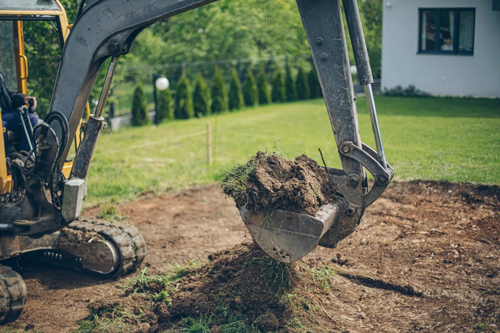 Excavator bucket breaking ground for a septic system