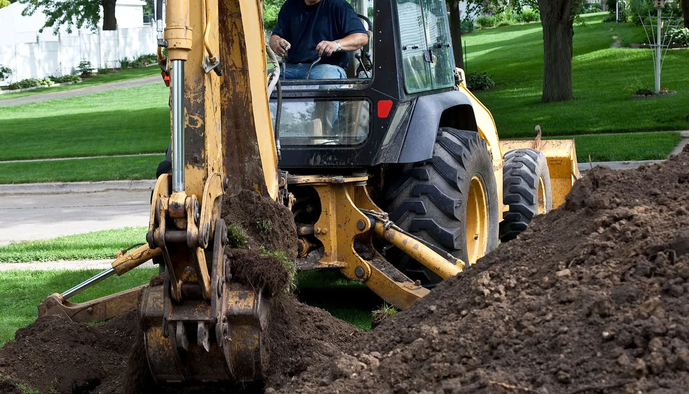 Backhoe digging a trench in a lawn for septic work
