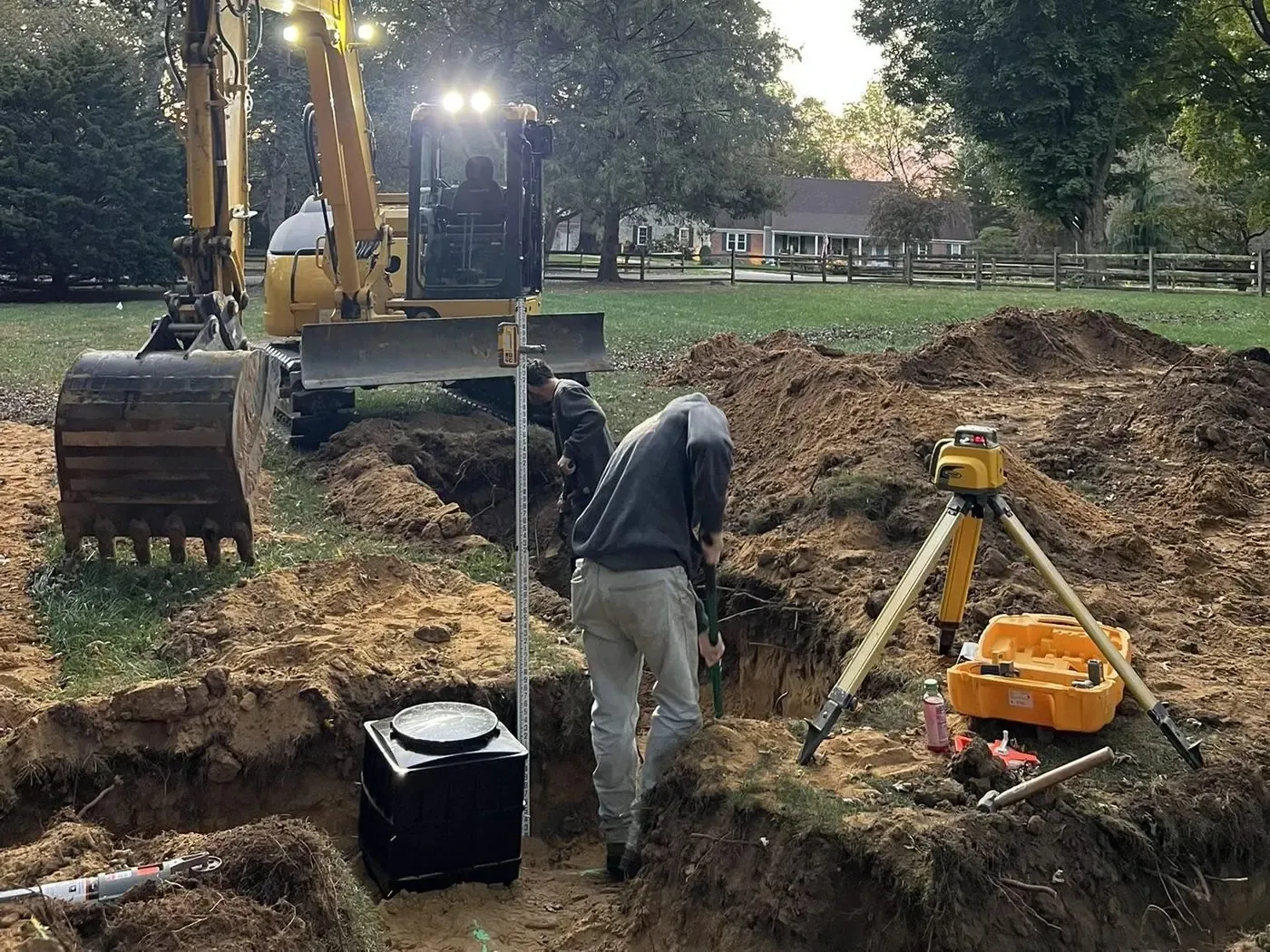 Crew checking grade with a laser level in a septic tank excavation