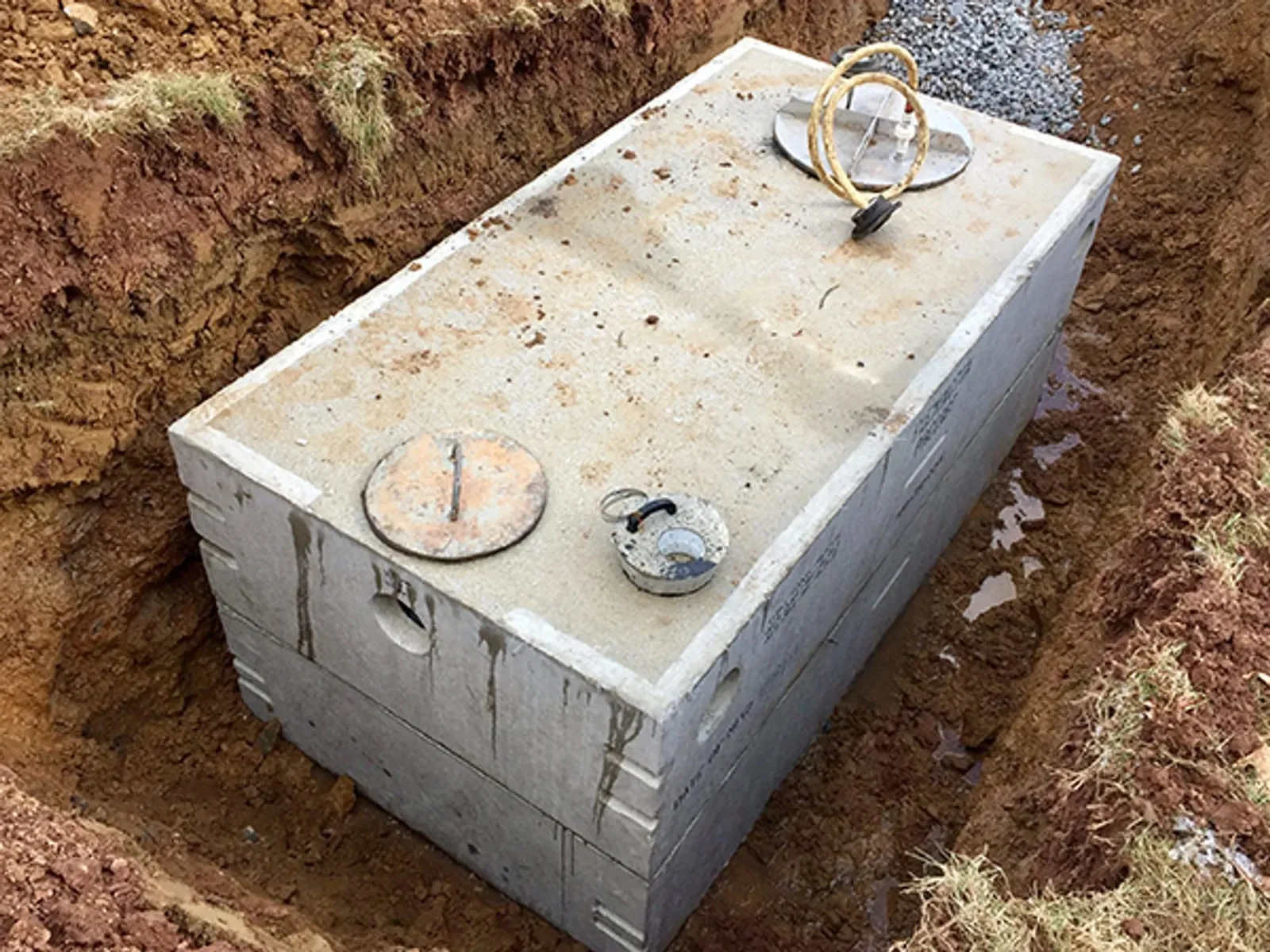 Concrete septic tank set in a red clay excavation